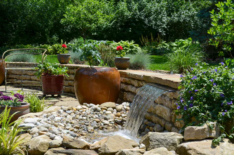 Ceramic urns and a narrow waterfall rill set into natural stone and river rock